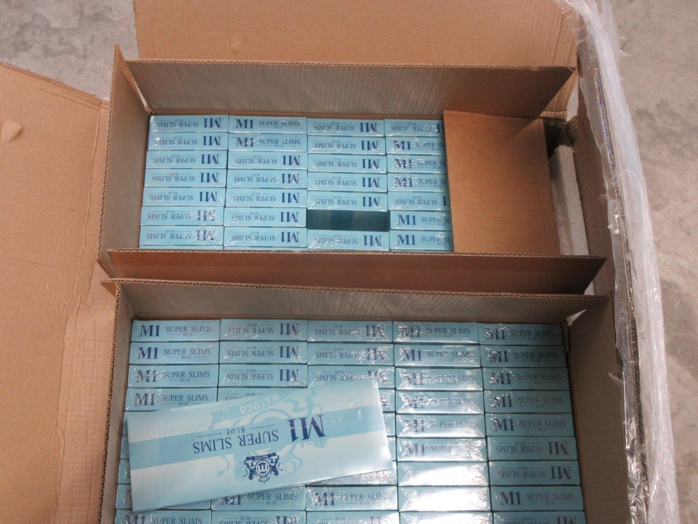 Atvērta kartona kaste ar cigarešu M1 Super Slim Blue iepakojumiem