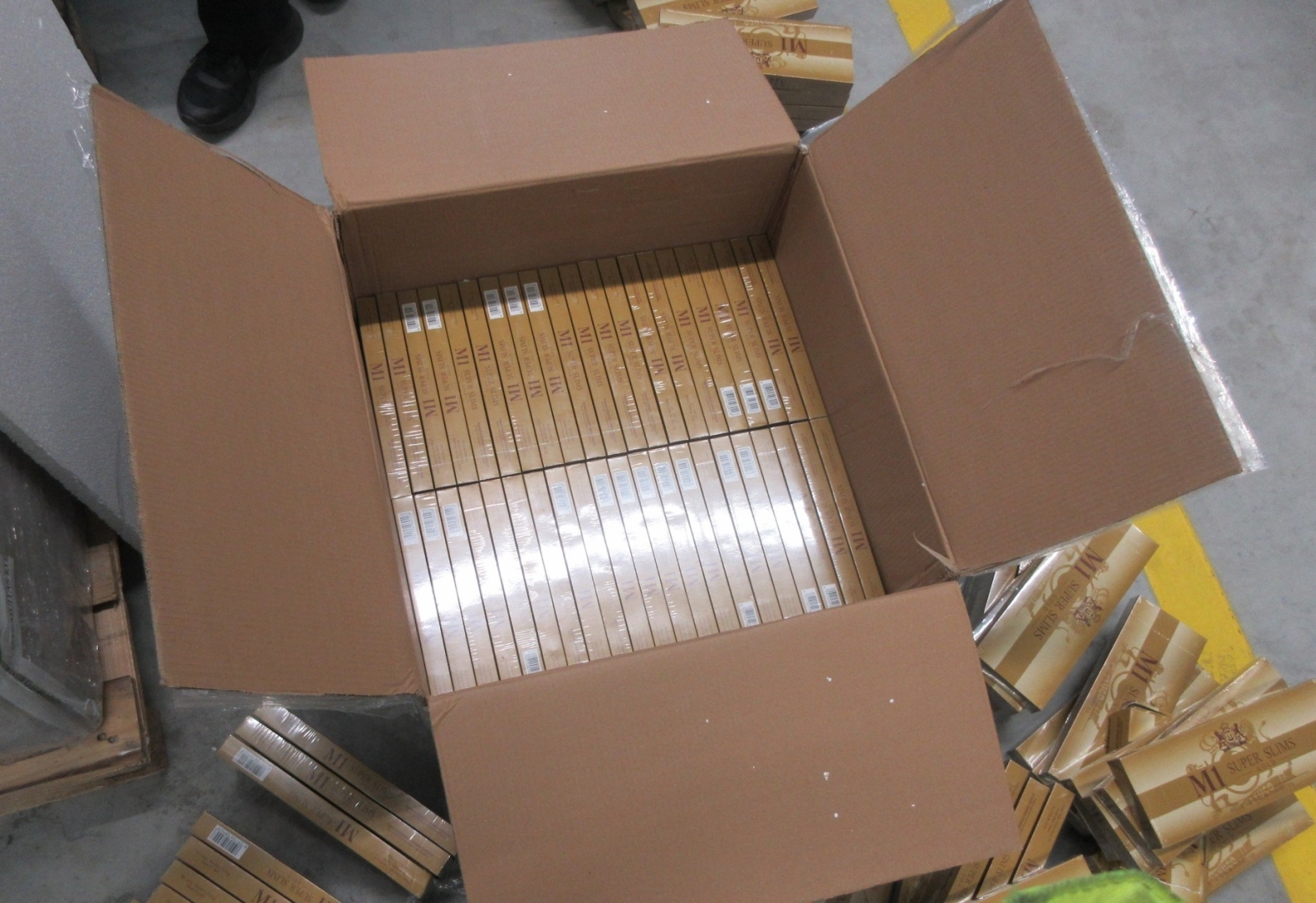Atvērtā kartona kastē iepakojumi ar kontrabandas cigaretēm M1 Super Slims Gold 