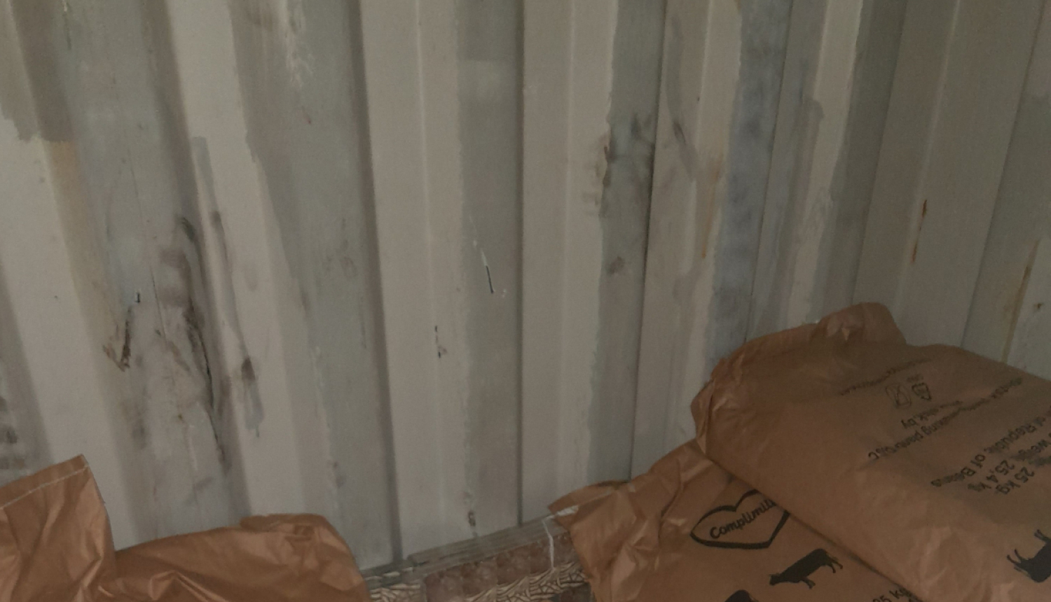 Pie vagona gala sienas aiz maisiem ar sauso pienu stāv paslēptas kontrabandas cigarešu paciņas