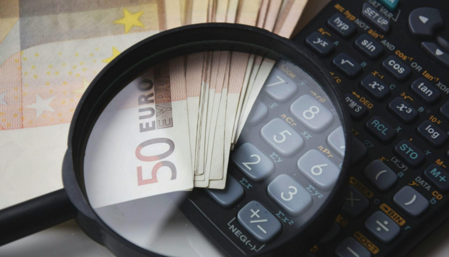 Palielināmais stikls uz eiro banknotes un kalkulatora