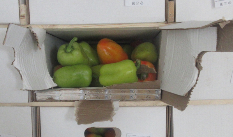 Kastē zaļa un sarkana paprika, gar malu – cigarešu paciņas 