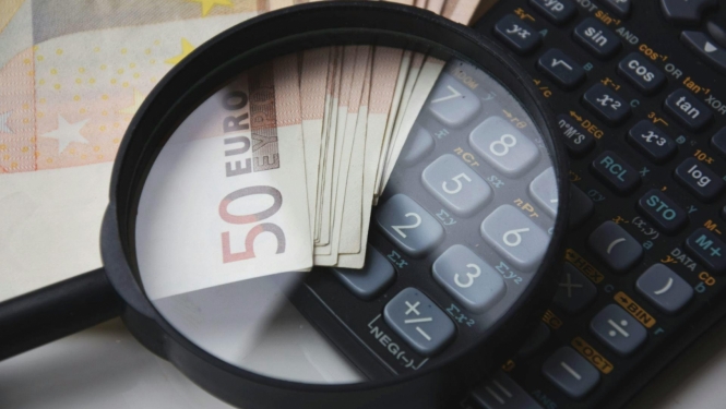 Palielināmais stikls uz eiro banknotes un kalkulatora