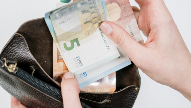 Cilvēka rokās naudas maks ar banknotēm