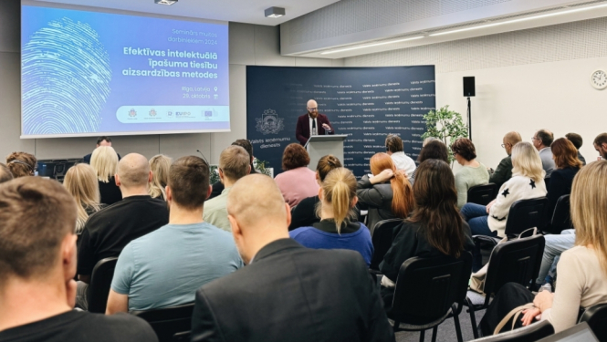 Patentu valdes foto: zālē sēž cilvēki priekšā stāv lektors