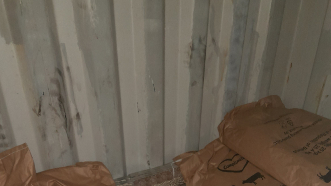 Pie vagona gala sienas aiz maisiem ar sauso pienu stāv paslēptas kontrabandas cigarešu paciņas