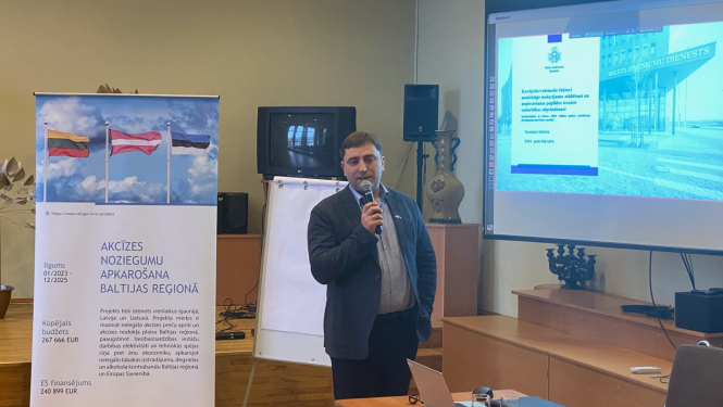 Nodokļu un muitas policijas direktors pie banera runā mikrafonā 