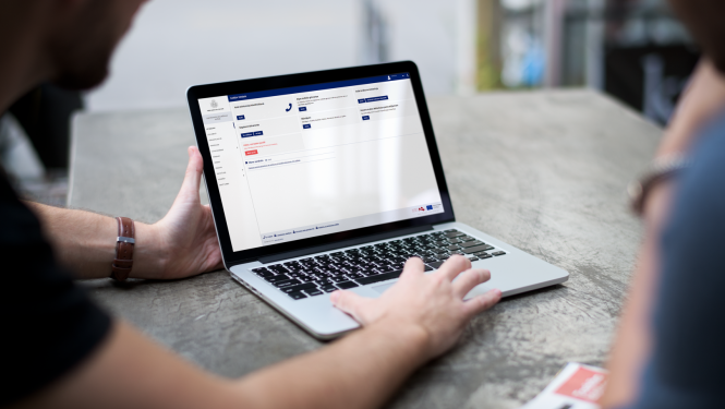 Atvērts portatīvais dators ar rokām uz klaviatūras 
