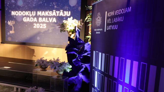 Banneris ar uzrakstu "Nodokļu maksāt'ju gada balva" ziedu dekorācijas