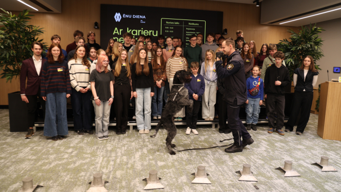 Ēnu dienas dalībnieku kopbilde, priekšplānā kinologs ar savu darba suni