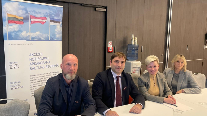 Divas sievietes un divi vīrieši pie galda oficiālā pasākumā 