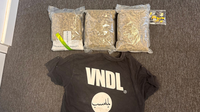 Uz grīdas trīs nelieli caurspīdīgi plēves iepakojumi ar brūnas krāsas narkotiskajām vielām 