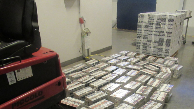 Uz grīdas kaudzēs sakārtoti daudz cigarešu bloki 