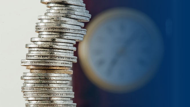 Monētas kaudzītē, fonā pulkstenis