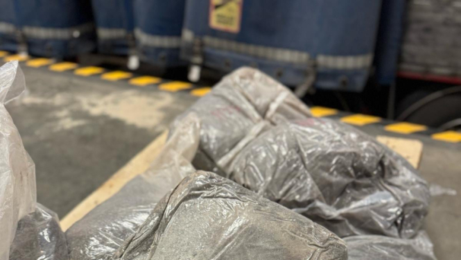 Tuvplānā redzami plēvē ietīti vairāki iepakojumi ar tumšu vielu 