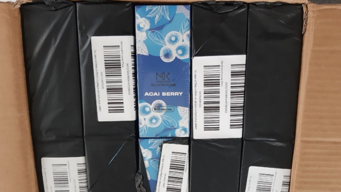 Atvērta kaste ar melnā plēvē iepakotām elektroniskajām cigaretēm 