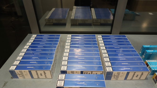 Uz metāla galda stāv kontrabandas cigarešu paciņas 