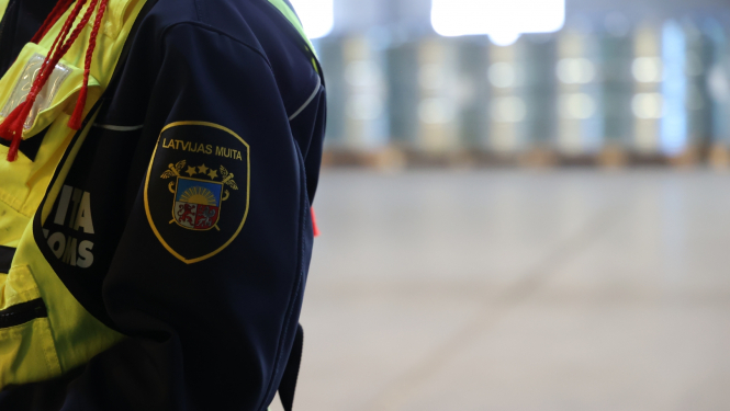 Muitas darbinieka plecs ar ģērboni bildes kreisajā pusē