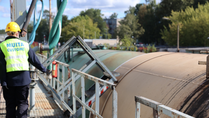 Muitas darbinieks uz estakādes pie cisternas