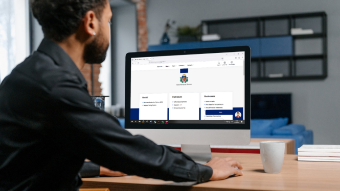 Cilvēks sēž pie datorgalda, ekrānā atvērta vid.gov.lv/eng tīmekļvietne