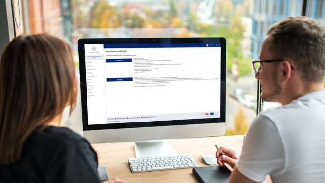 Divi cilvēki skatās datora ekrānā