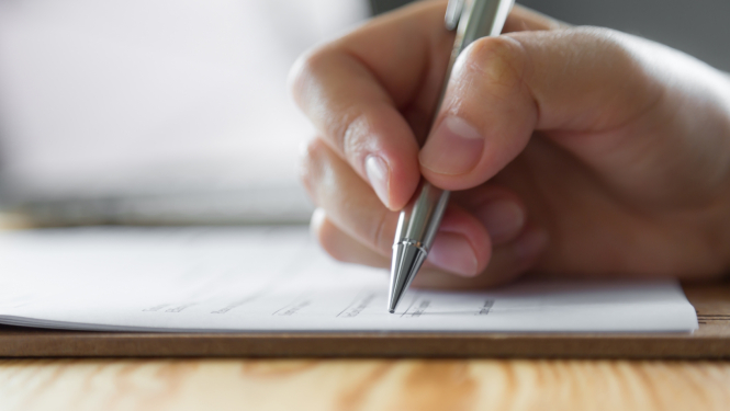 Roka tur pildspalvu un raksta uz papīra