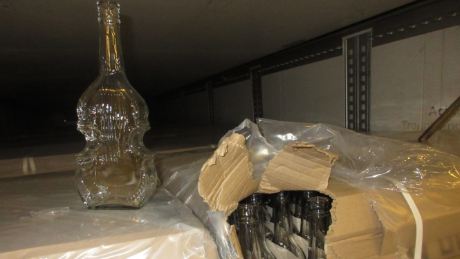 Stikla pudele vijoles formā uz kartona kastēm ar stikla pudelēm vijoles formā 