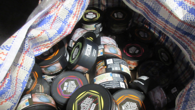 Rūtaina soma pilna ar krāsainām tabakas bundžiņām  