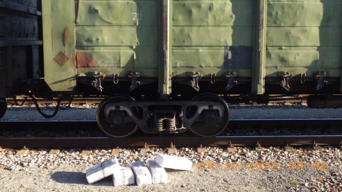 Blakus vilciena vagonam stāv baltā plēvē ietītas pakas, kurās atrodas kontrabandas cigaretes