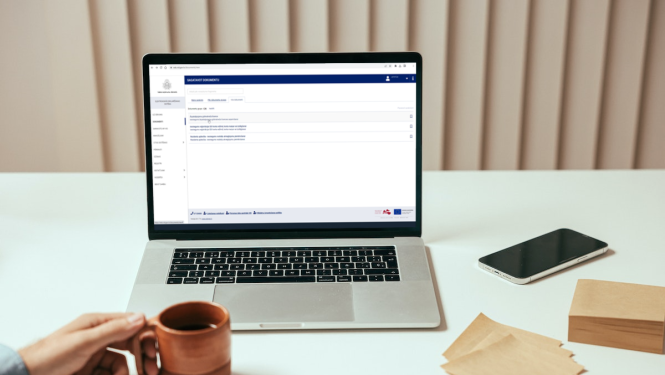 Uz galda novietots atvērts portatīvais dators, viedtālrunis un piezīmju lapiņas