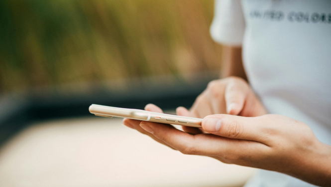 Sieviete tur rokās mobilo telefonu