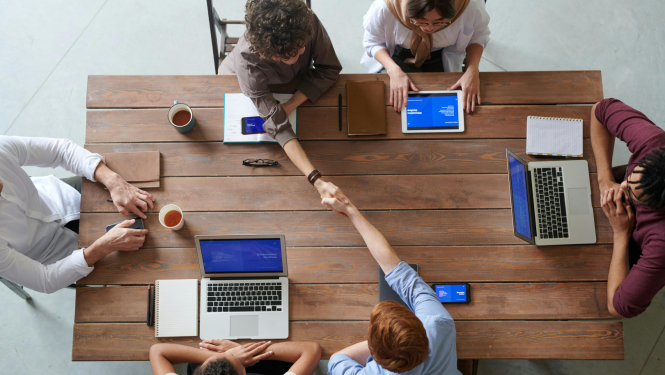 Skats no augšas, vairāki cilvēki sēž pie galda