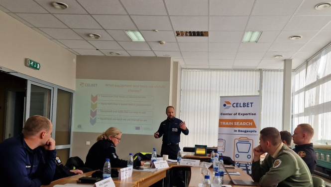 Muitas speciālisti pie galda klausās lektora stāstījumu