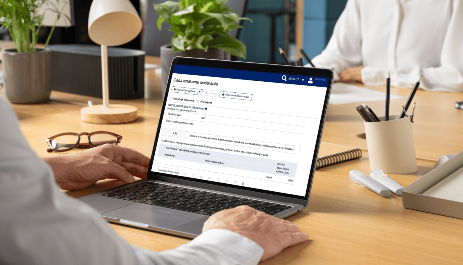 Atvērts portatīvais dators uz galda, ekrānā EDS Gada ienākumu deklarācija