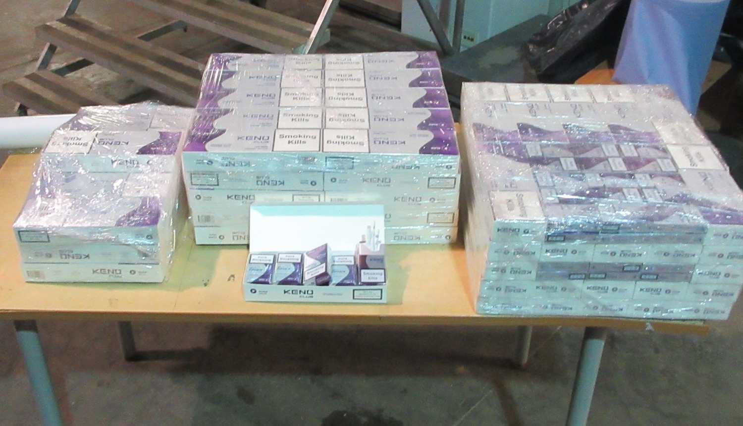 Plēvē ietītas daudz cigarešu paciņas saliktas uz galda 