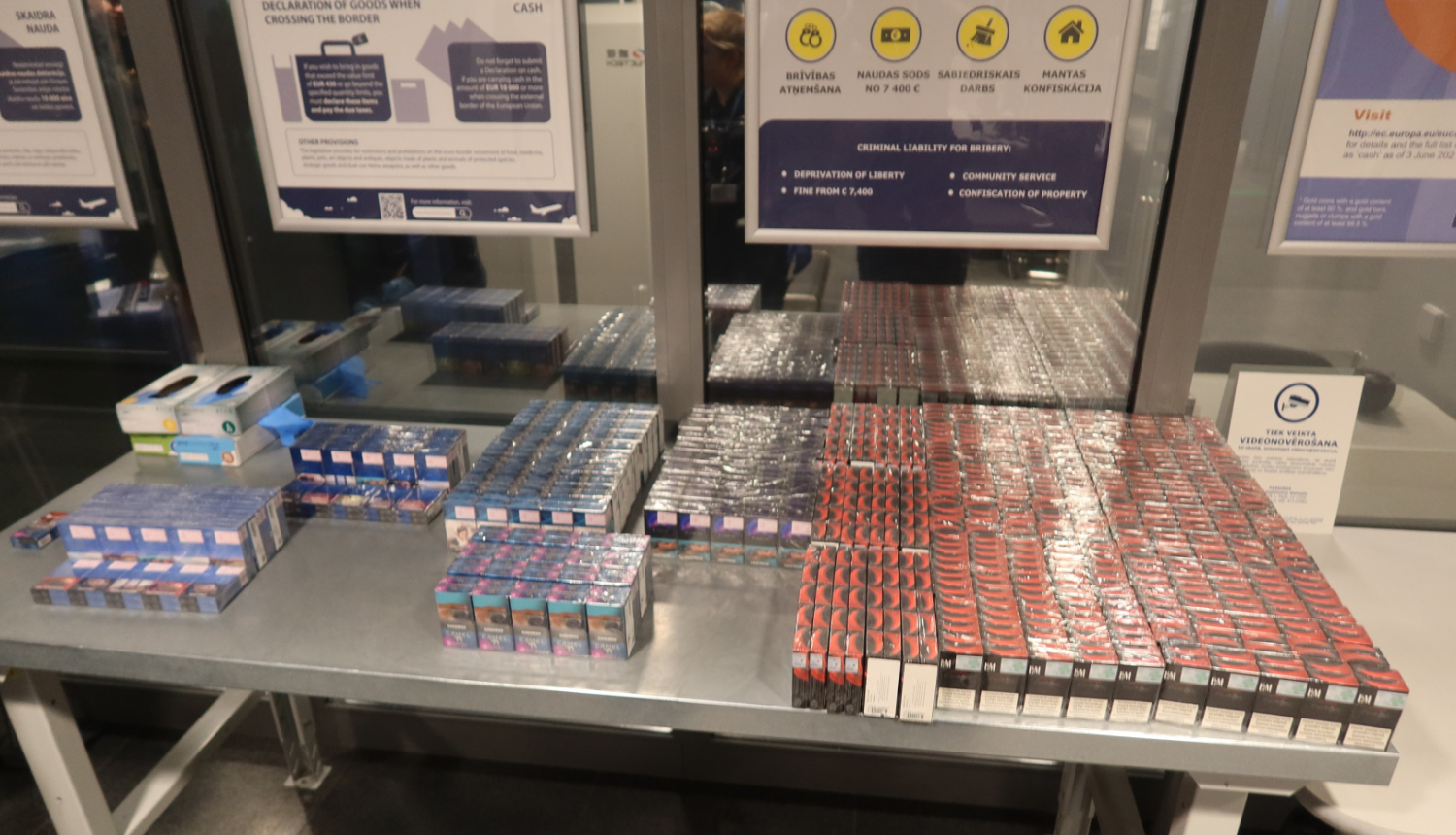 Daudz zilas un sarkanas cigarešu paciņas uz metāla galda