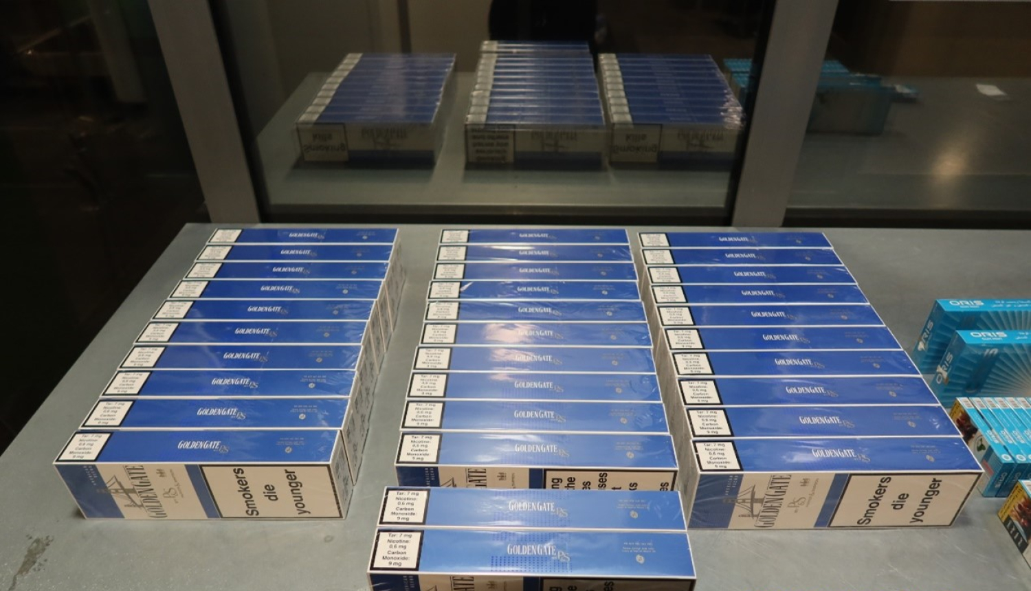 Uz metāla galda stāv kontrabandas cigarešu paciņas 