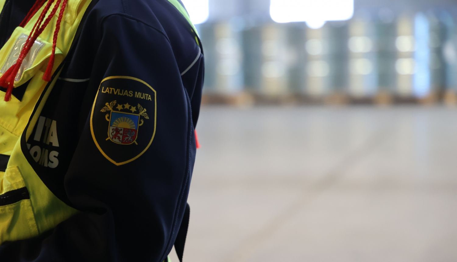 Muitas darbinieka plecs ar ģērboni bildes kreisajā pusē