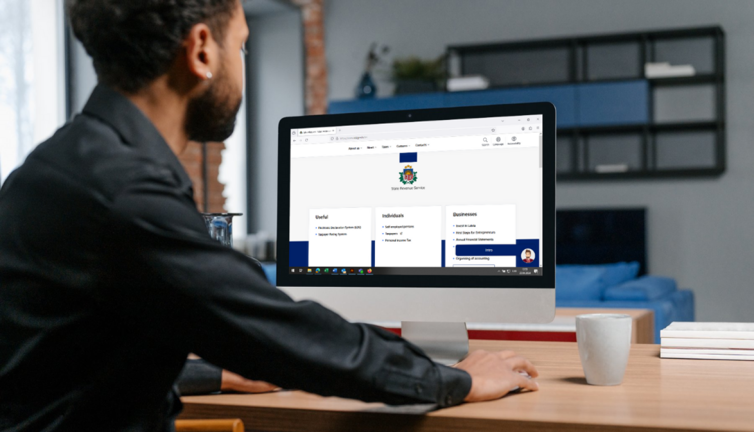 Cilvēks sēž pie datorgalda, ekrānā atvērta vid.gov.lv/eng tīmekļvietne