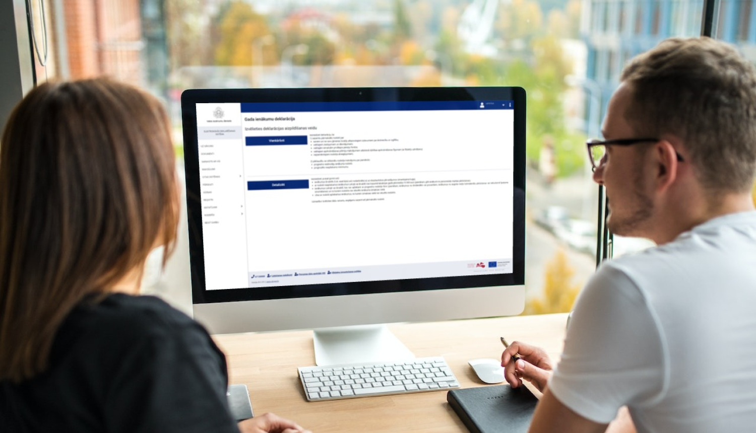 Divi cilvēki skatās datora ekrānā