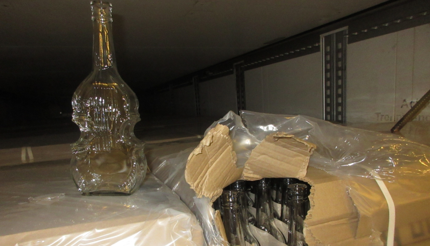 Stikla pudele vijoles formā uz kartona kastēm ar stikla pudelēm vijoles formā 