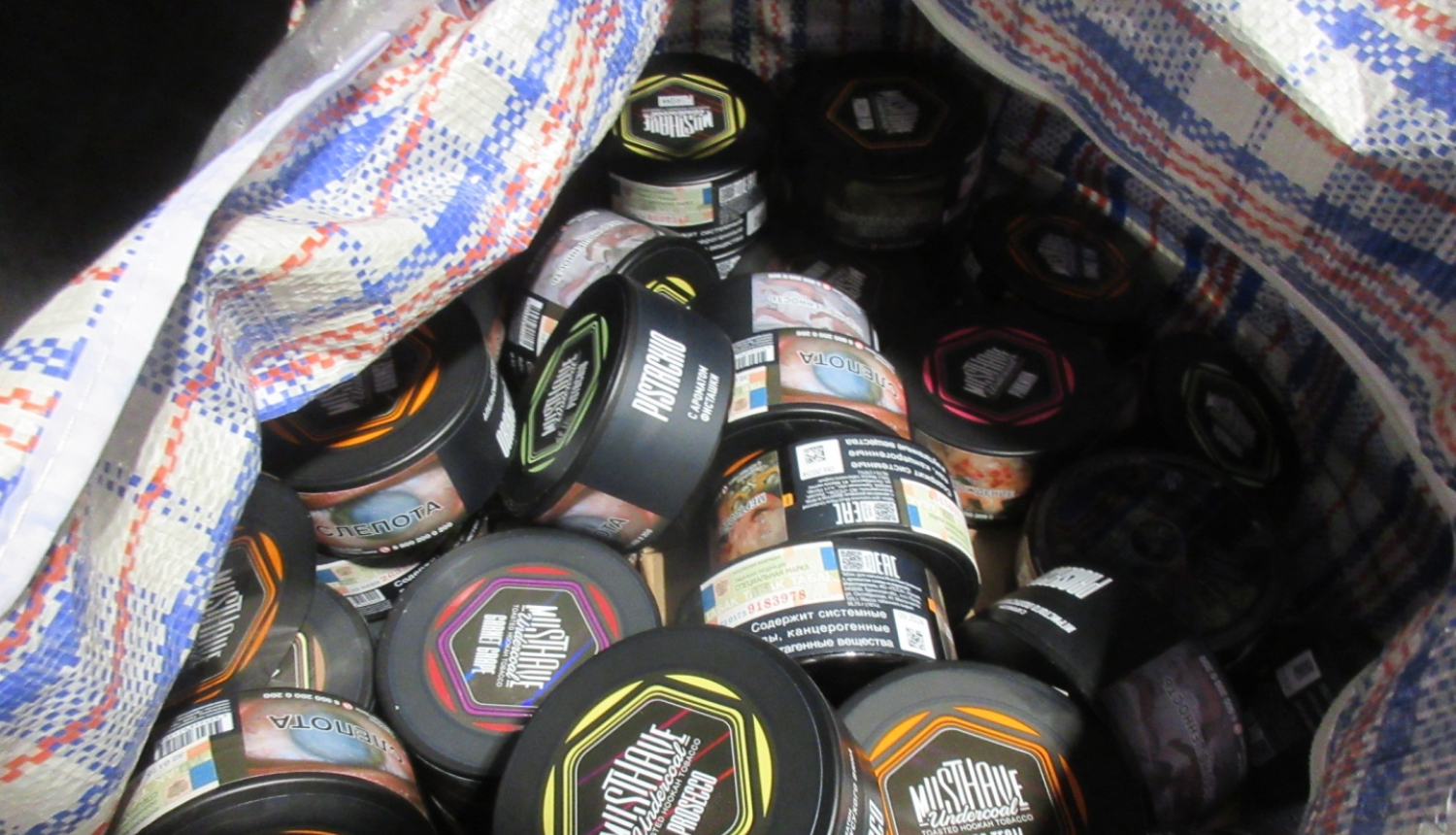 Rūtaina soma pilna ar krāsainām tabakas bundžiņām  