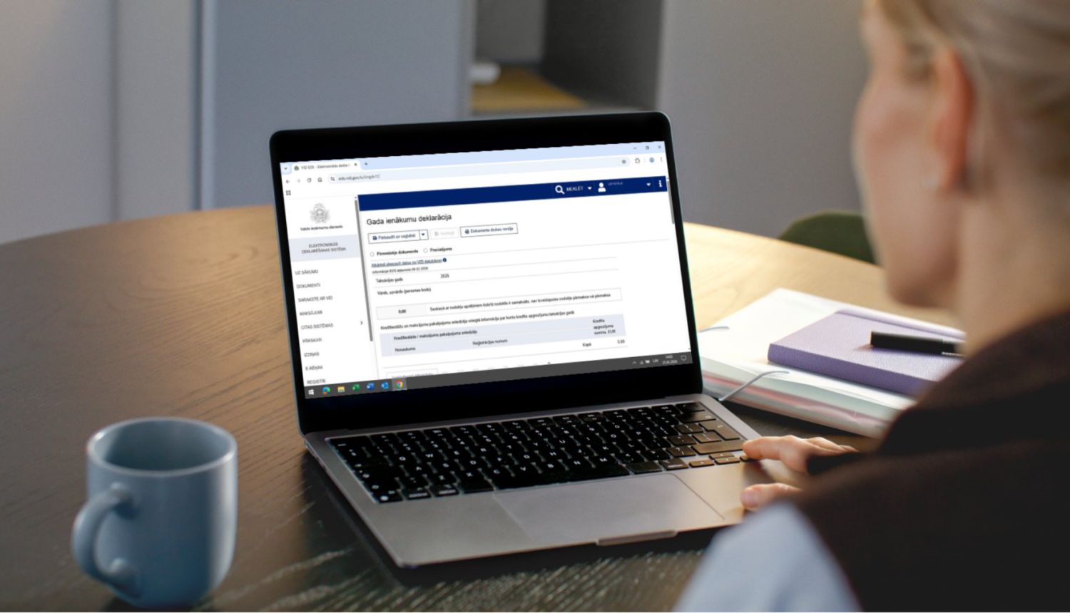 Uz galda atvērts portatīvais dators, ekrānā GID 