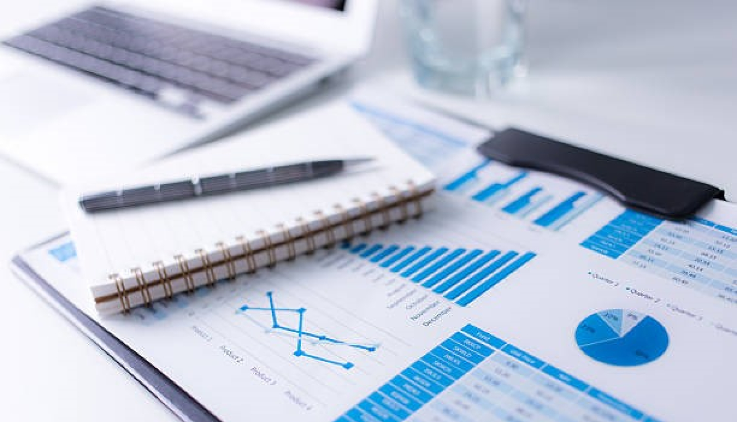 Uz galda bloknots ar pildspalvu un attēls ar diagrammām