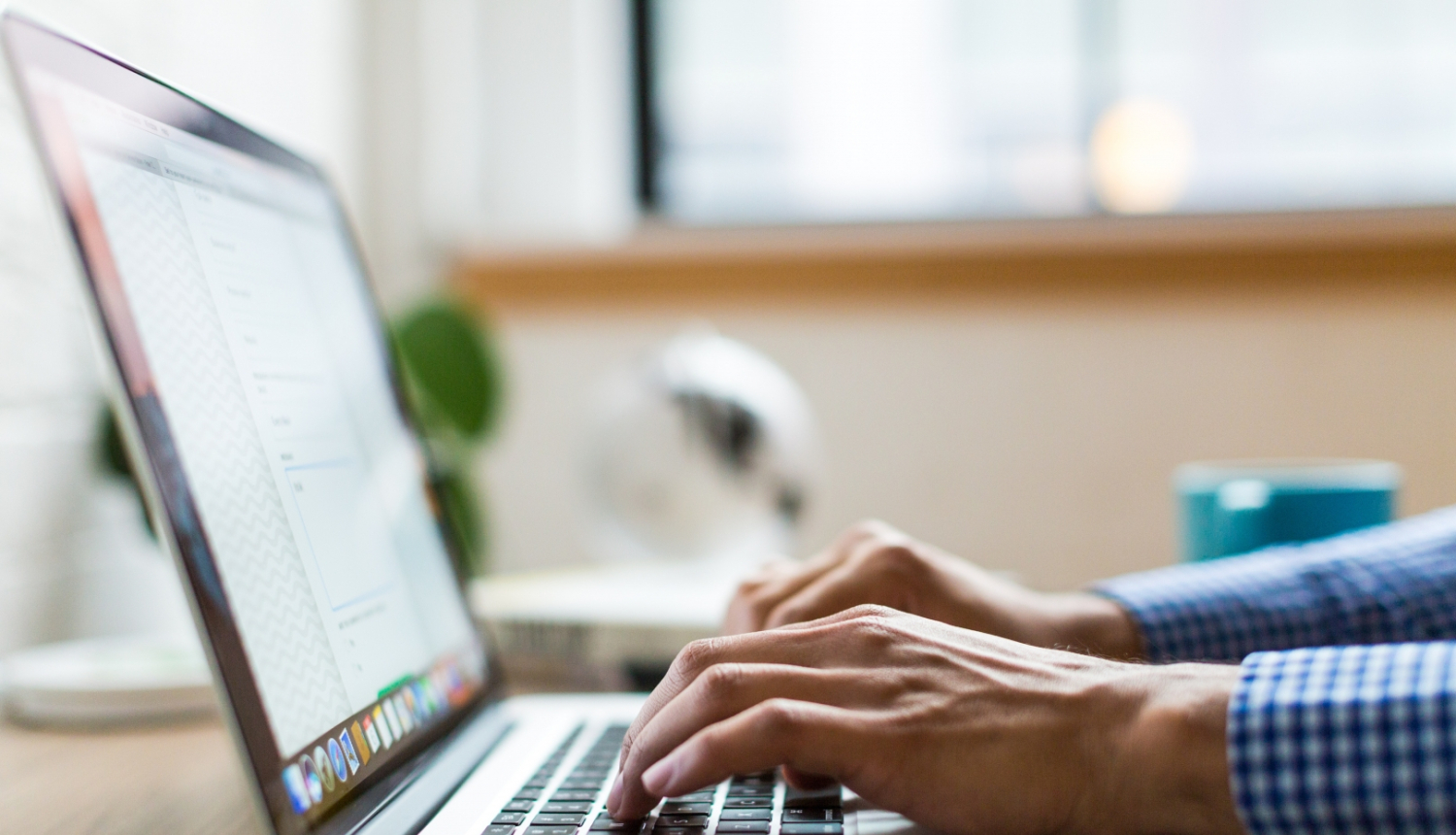 Atvērts portatīvais dators ar rokām uz klaviatūras 