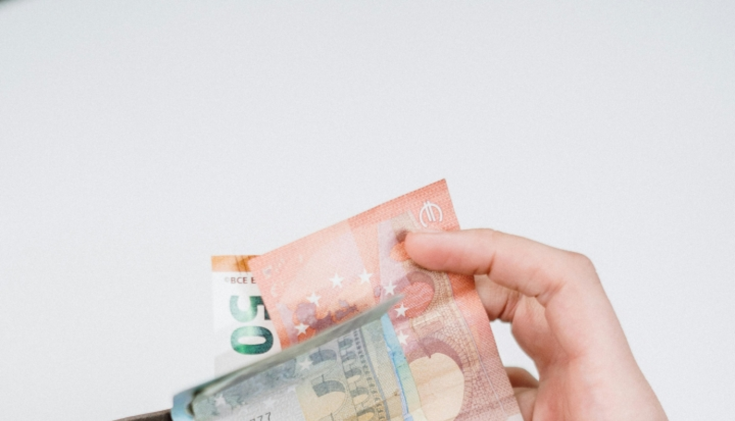 Cilvēka rokās naudas maks ar banknotēm