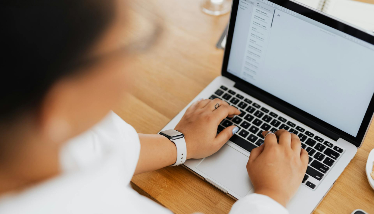 skats no augsās, cilvēks uzlicis rokas uz portatīvā datora klaviatūras