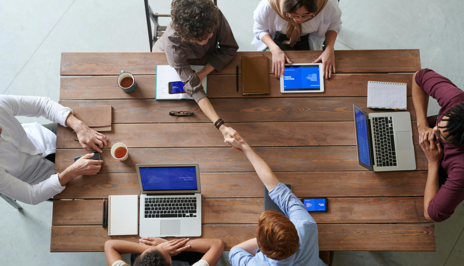 Skats no augšas, vairāki cilvēki sēž pie galda