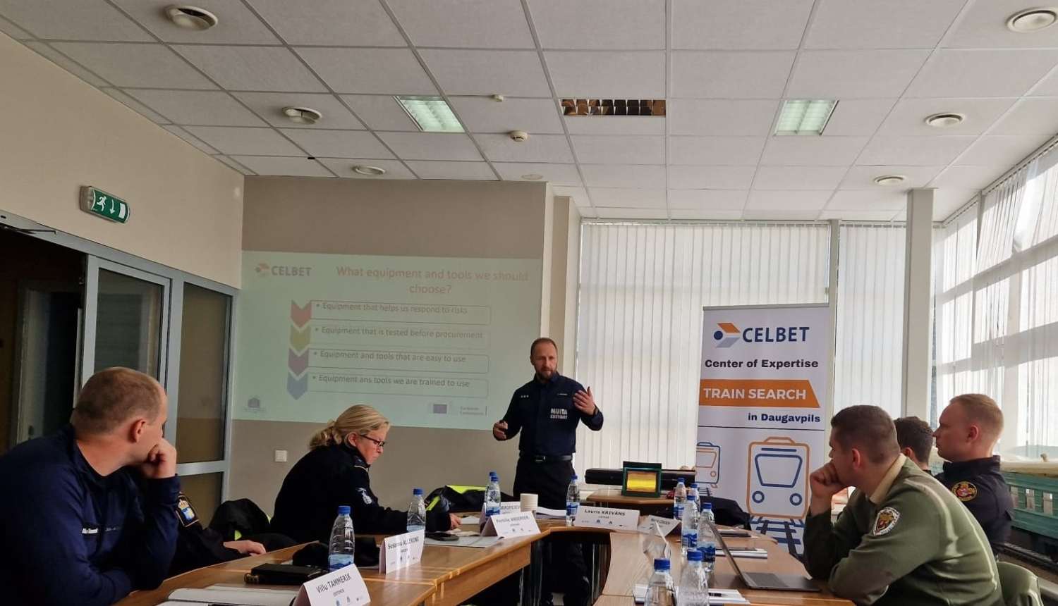 Muitas speciālisti pie galda klausās lektora stāstījumu