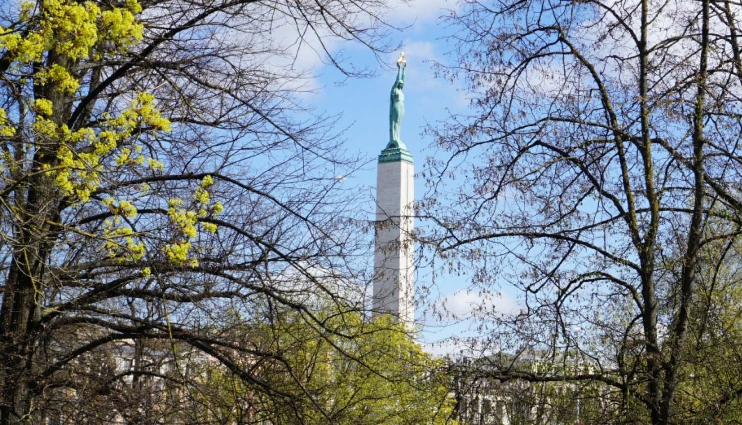 Skats uz Brīvības pieminekli caur kokiem 