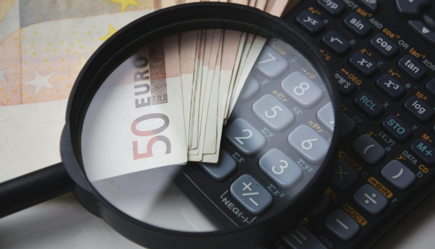Palielināmais stikls uz eiro banknotes un kalkulatora